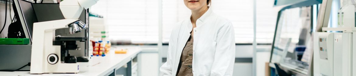 Horizontal portrait of a female scientist siiting in a modern laboratory and smiling to camera